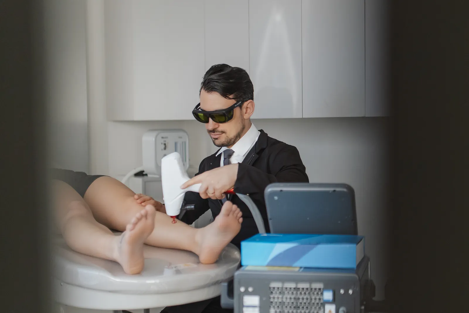 Dr. Rafael Giacobbo aplicando laser na perna de uma paciente no consultório da Laviniq